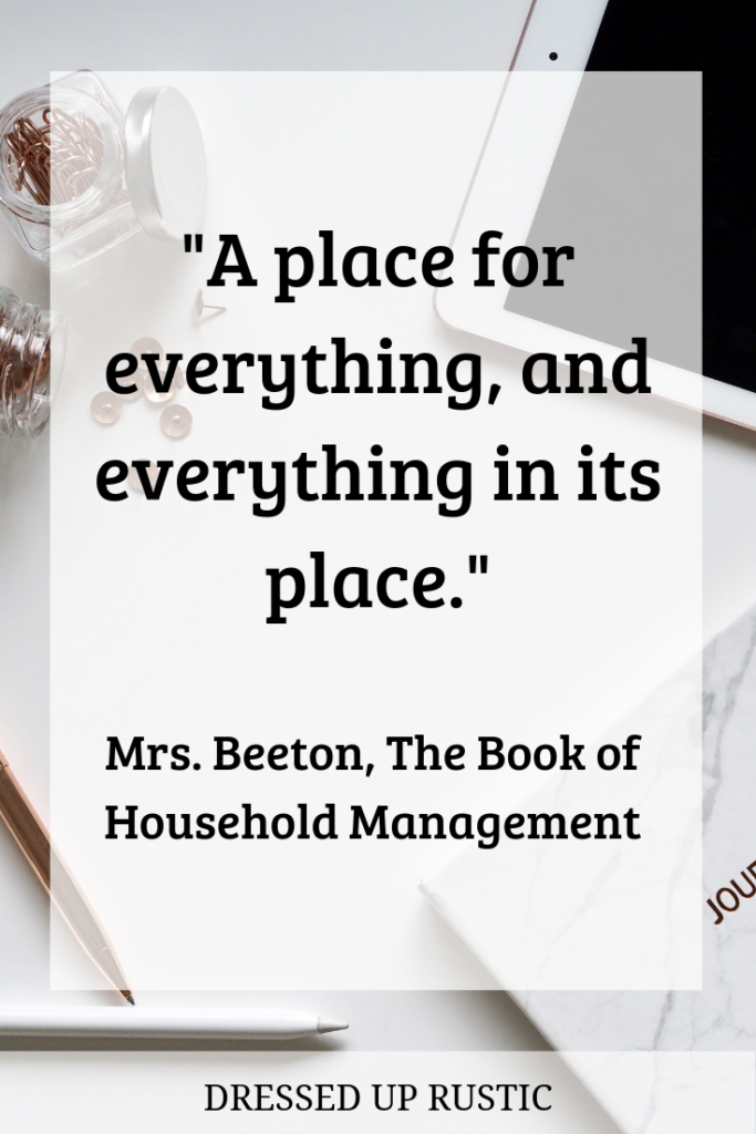 Organization Quote by Mrs. Beeton, from The Book of Household Management. It's layered over a white desktop of stuff, including gold paperclips, gold brads, gold tacks, an ipad or smartphone, a white journal, and a white pen and a gold pen. The picture is meant to symbolize clutter that takes up space and has no home in the house. The quote is meant to motivate and inspire you to create an organized home and declutter your spaces.